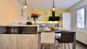 A modern kitchen with a central island, white chairs, and a dining table. - La Maison Bleue - Comfortable appt Gr34 (Locmaria-Plouzané)