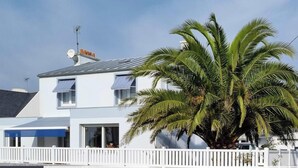 A two-story building with a white facade, a satellite dish, and a white picket fence. - La Maison Bleue - Comfortable appt Gr34 (Locmaria-Plouzané)