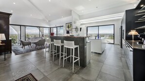 Una cocina amplia con una isla central, taburetes de bar y un ventanal con vistas.