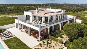 Una casa moderna de dos plantas con terraza en la azotea, piscina y jardín cuidado.