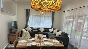 Un salon moderne avec un coin repas, comprenant un ensemble de canapés, un téléviseur et une table à manger pour quatre personnes.