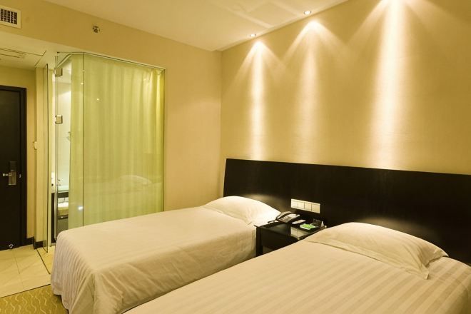 Een hotelkamer met twee bedden, een nachtkastje, een spiegel en een deur naar een badkamer.
