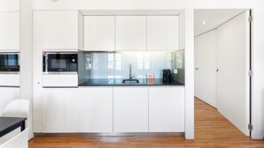 A modern kitchen with white cabinetry, a black countertop, and a built-in microwave.