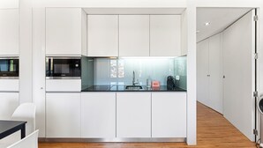 A modern kitchen with white cabinetry, a Bosch microwave, and a coffee machine.