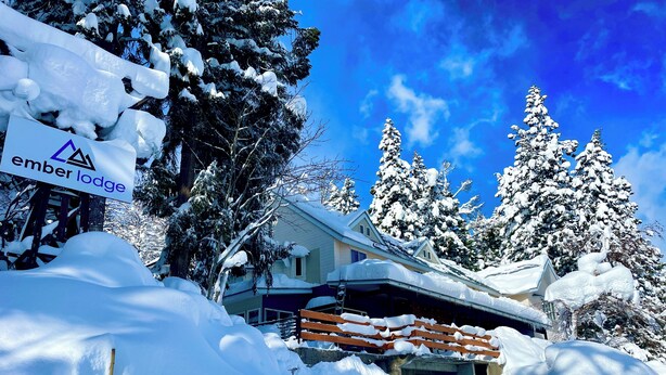Eine schneebedeckte Lodge mit einem Schild, auf dem "ember lodge" steht.
