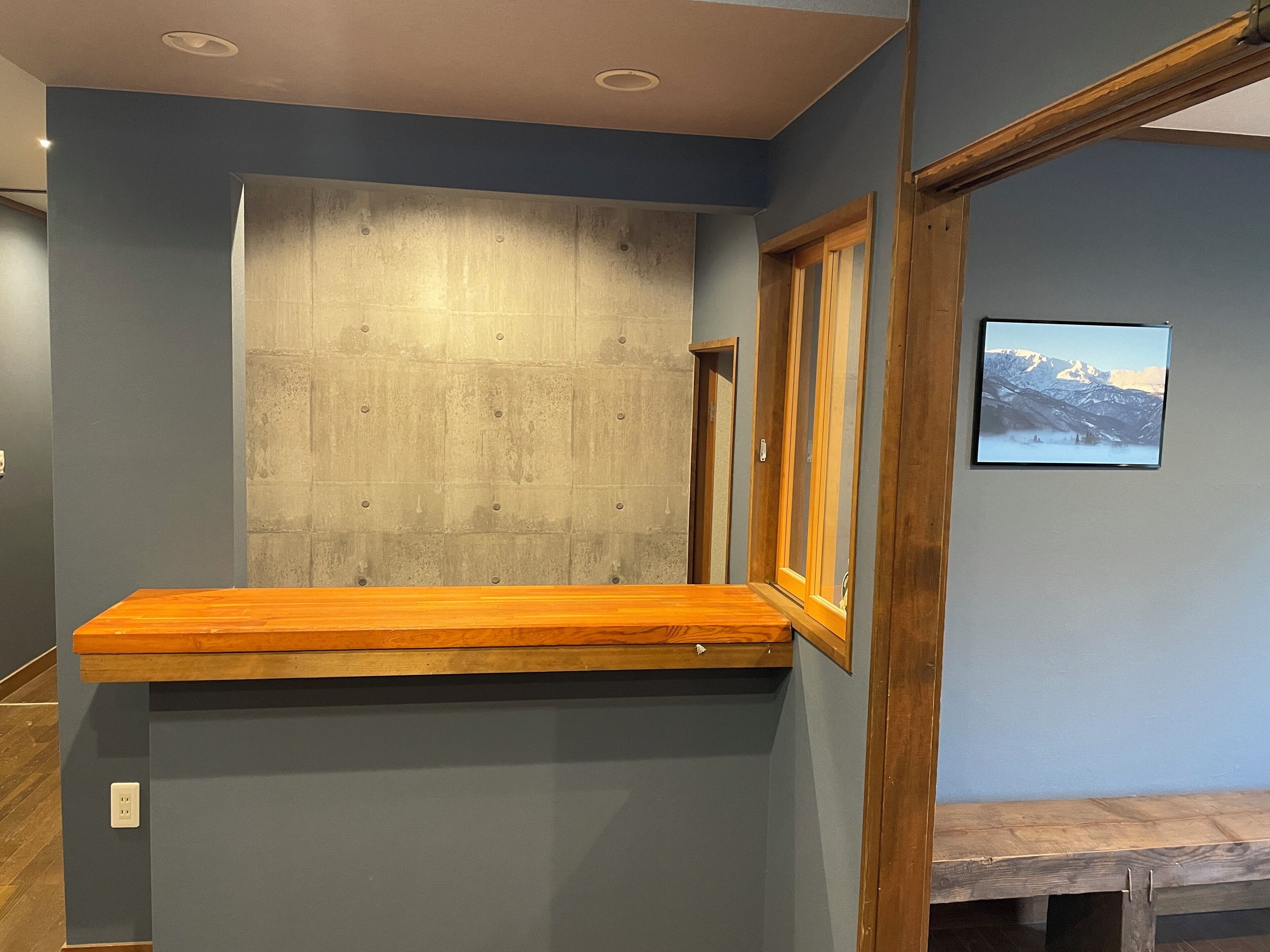 A room with a wooden bench, a concrete accent wall, and a framed picture on the wall.