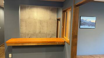 A room with a wooden bench, a concrete accent wall, and a framed picture on the wall.