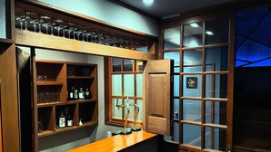 Eine Barbereitschaft mit Regalen voller Weinkelchen, Flaschen und einem Zapfhahn.