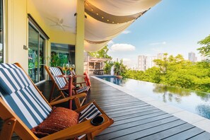 A rooftop infinity pool with lounge chairs and a canopy, overlooking a cityscape and lush greenery. -  38Pax Flame of the Forest Retreat Villa KL by Verano (Kuala Lumpur)