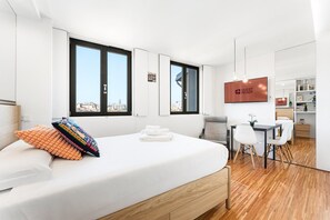 A modern hotel room with a large bed, a desk, and a view of the city. - GuestReady - Cathedral Design Apartments - Sé (Porto)