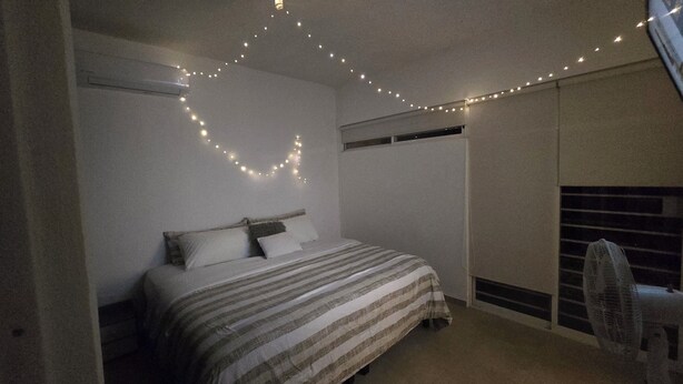 Un dormitorio con cama, ventana y ventilador.