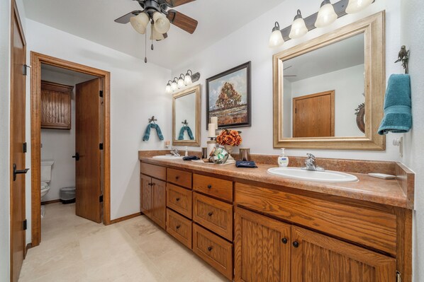 A bathroom with wooden cabinetry, a large mirror, and a ceiling fan. - Two Homes on 160 Acres. Stocked Ponds, Firepits. Just 30 minutes from Tulsa. (Coweta)