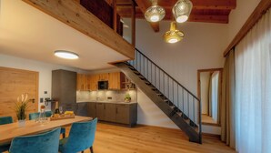 Une cuisine moderne avec un plancher en bois, un coin repas avec des chaises bleues et un escalier doté d’une rampe en métal.