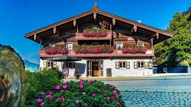 Un bâtiment traditionnel en bois, doté de balcons, une enseigne indiquant un restaurant et une rue pavée.