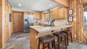 Una cocina con armarios de madera, encimera de granito y refrigerador de acero inoxidable.