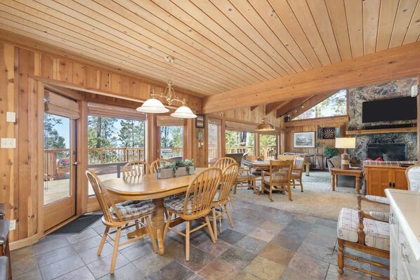 A spacious wooden interior with a large dining table, chairs, and a fireplace.