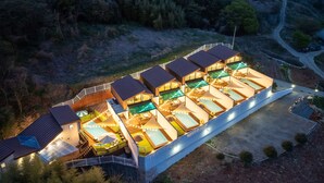 Een modern resort met diverse bungalows, een centraal gelegen zwembad en een goed verlichte buitenterrein.