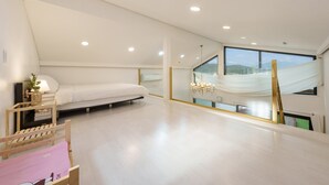 Een ruime slaapkamer met een bed, een nachtkastje met lamp, een groot raam met uitzicht en een kroonluchter.