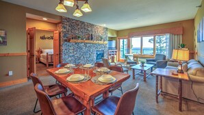 A dining area with a stone wall, a fireplace, and a view of the outdoors. - Two Harbors Superior Lakefront 2BR | Pool | Hot Tub & Sauna | EV Charger (Two Harbors)