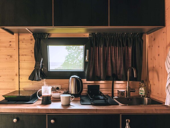 Cocina compacta con ventana, hervidor, cafetera, lavamanos y un armario.
