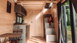 Interior acogedor de una cabaña de madera con kitchenette, comedor y escalera que sube a un altillo.