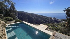 A clear blue pool with a view of the sea and mountains.