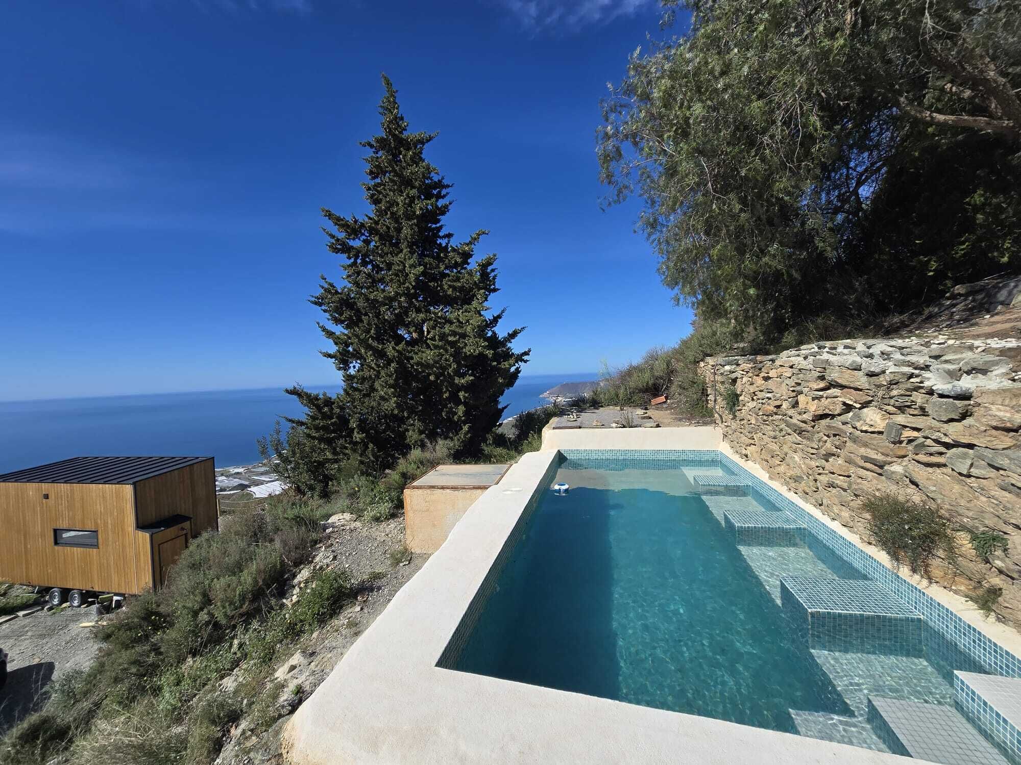 Une piscine à l’eau d’un bleu cristallin, entourée d’un paysage naturel et offrant une vue sur la mer.