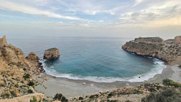 A coastal landscape with rocky terrain and a beach.