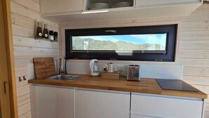 A compact kitchen with a wooden countertop, a built-in window, and a toaster.