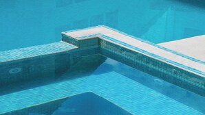 Une piscine avec une eau d’un bleu limpide, des marches carrelées et un couvercle d’évacuation.