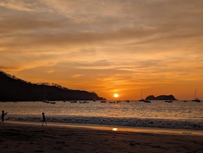 A beach scene with boats and a sunset.