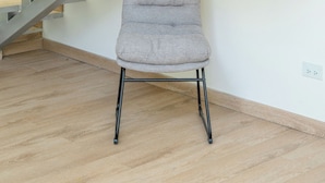 Un escalier moderne avec des rampes en métal et des marches en bois, un fauteuil rembourré de couleur grise et un plancher en bois.