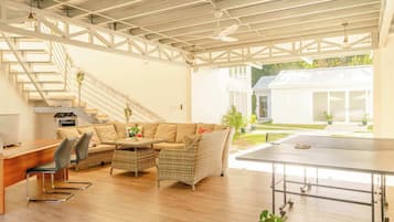 A spacious living area with a sofa set, a dining table, and a ping pong table.