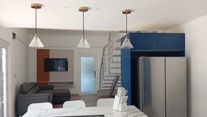 A modern kitchen with a built-in island, stainless steel appliances, pendant lighting, and a staircase leading to a living area.