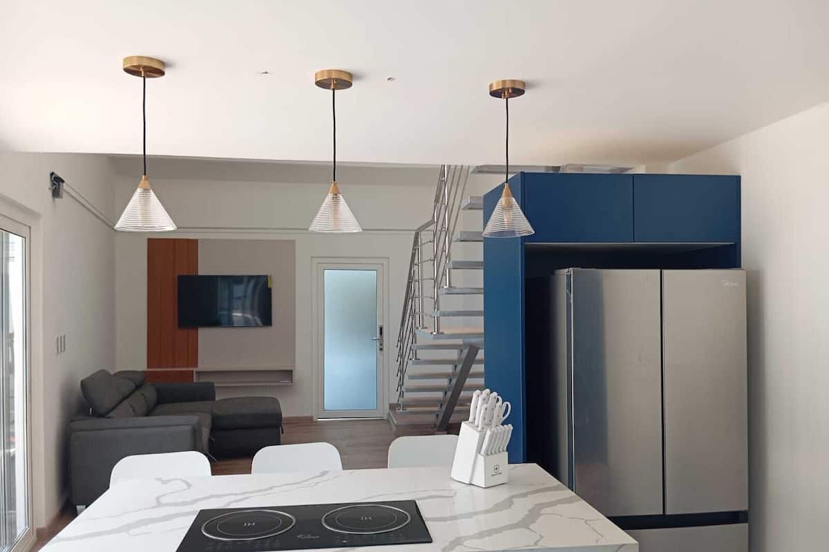 Una cocina moderna con una isla central, electrodomésticos integrados e iluminación colgante.
