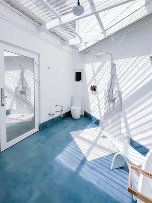 A modern bathroom with a glass door, a shower, a toilet, and a sink.