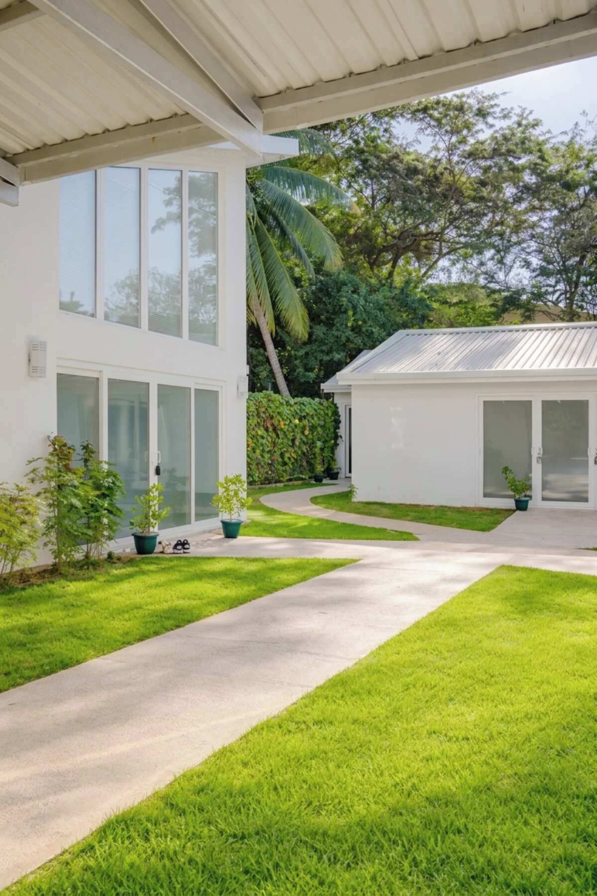 Een modern huis met een overdekt terras, een verzorgd gazon en een pad dat naar de ingang leidt.