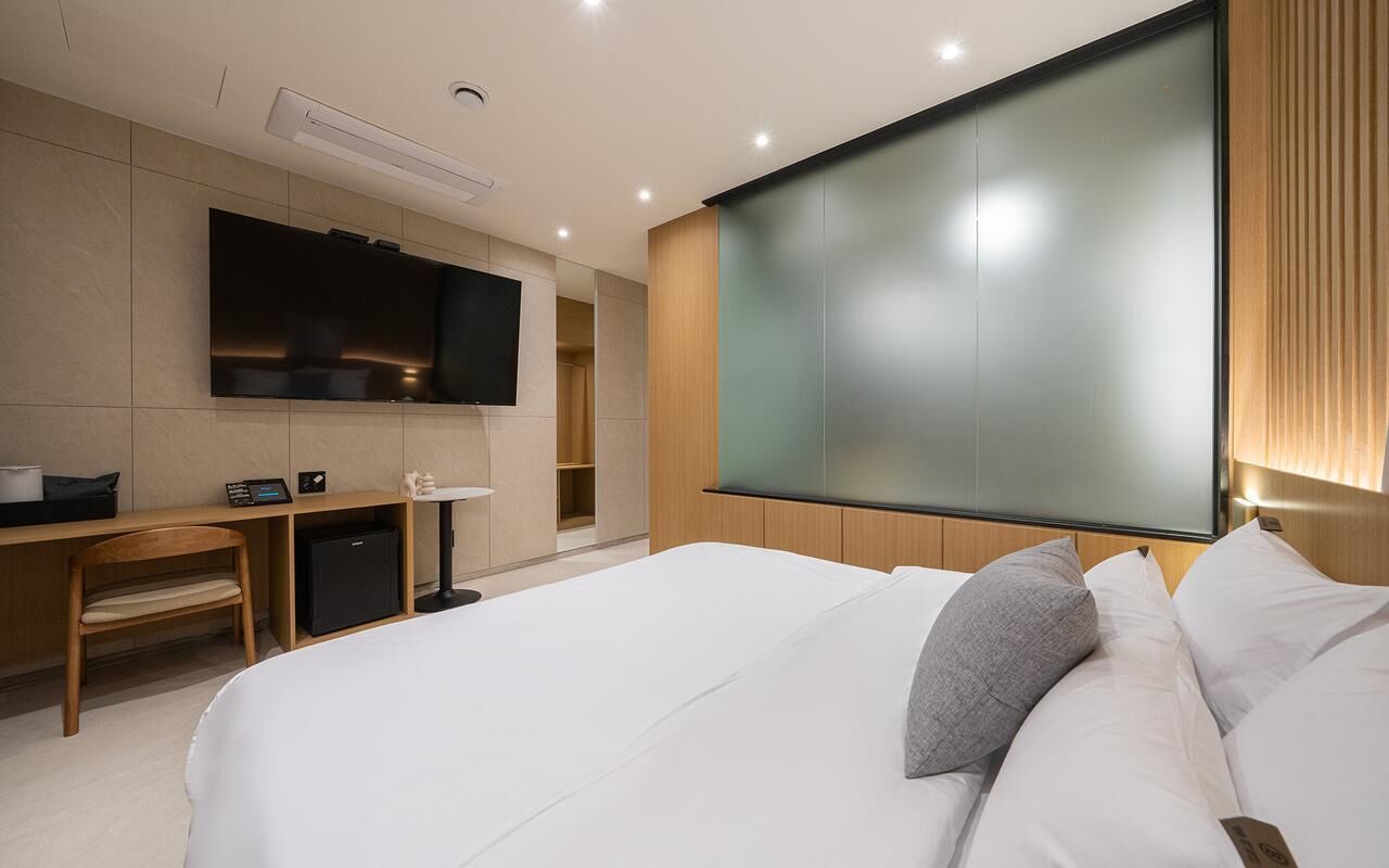 Una habitación de hotel moderna con una cama grande, un escritorio, un televisor y un minibar.