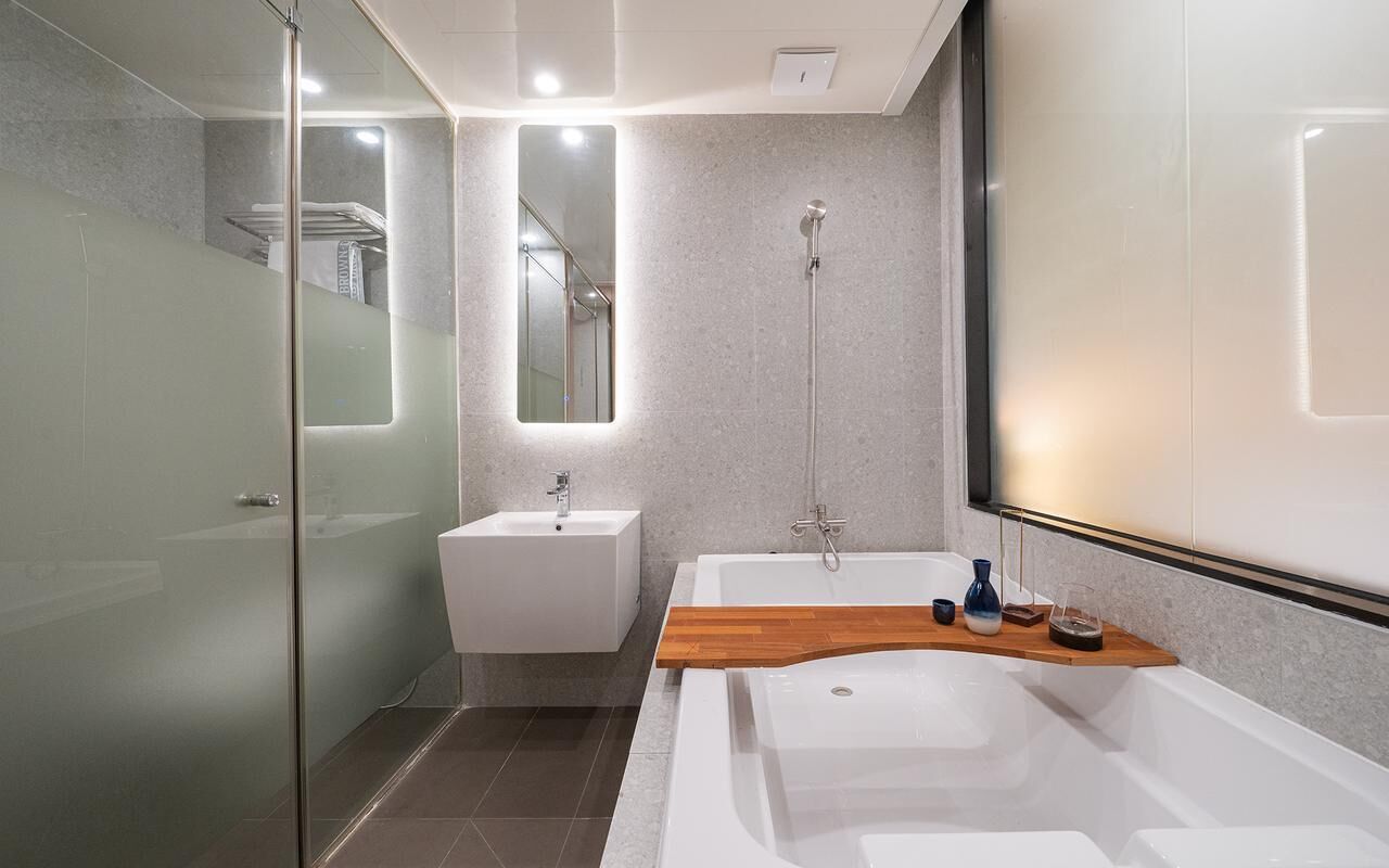 A modern bathroom with a glass shower enclosure, a white sink, and a large bathtub.