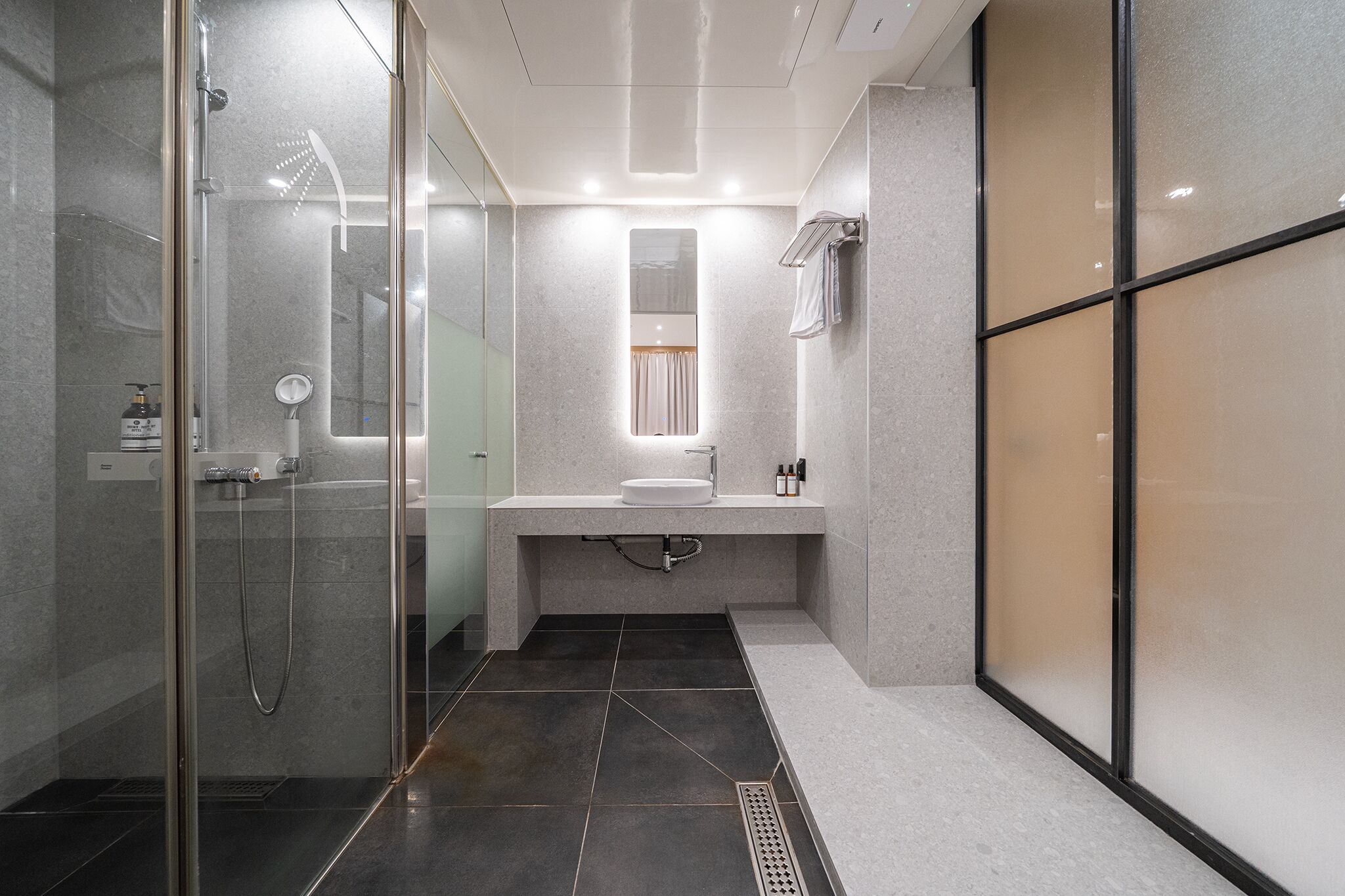 A modern bathroom with a glass shower enclosure, a vanity with a mirror, and a towel rack.