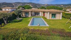 Una villa con piscina, jardín y vistas a las colinas.