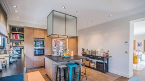 Una cocina moderna con una isla central, taburetes de bar y un horno empotrado.