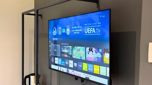 A flat-screen TV mounted on a wall displaying a sports event and various streaming services. - Seeds Hotel Bukit Bintang (Kuala Lumpur)