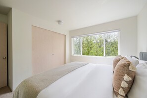 Relax in a serene space with a large bed, natural views, and a minimalist design.