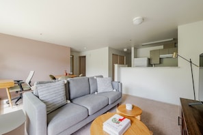 Relax in this stylish living room with a grey sofa, wooden coffee table, and a small round table with a lamp.