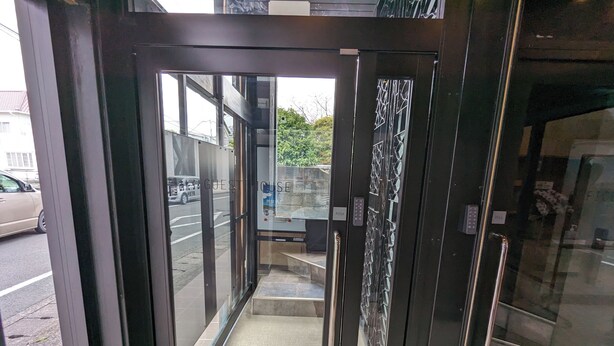 A hotel entrance with a glass door, a push button, and a small outdoor area with steps. - ATARAYO - Hostel (Shimoda)