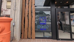 A building entrance with a glass door and wooden slats. - ATARAYO - Hostel (Shimoda)