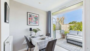 A dining area with a table set for four, a sofa, and a view of the garden.