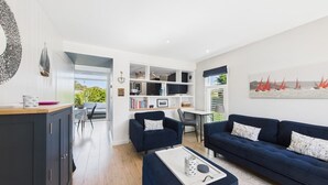 A modern living room with a dark blue sofa, a coffee table, and a bookshelf.