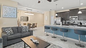 A modern kitchen with dark cabinets, stainless steel appliances, and a blue island with bar stools.